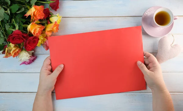 特写女性手牵着纸 空白的红色表格 一张祝贺卡片 一束玫瑰 母亲节的概念 设计师的复制空间 — 图库照片