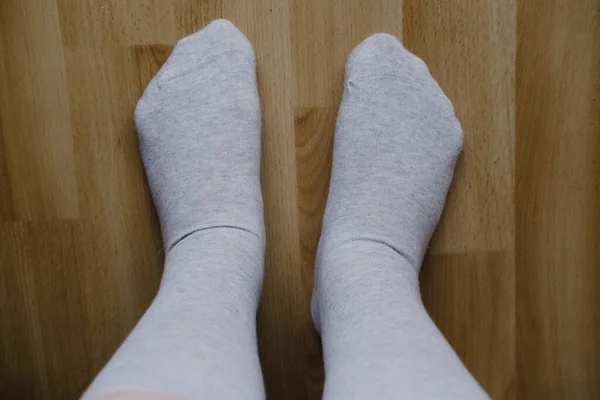 close-up of female feet on the floor in gray light cotton stockings, the concept of women\'s health, diseases of the veins, joints of the lower extremities, leg fatigue