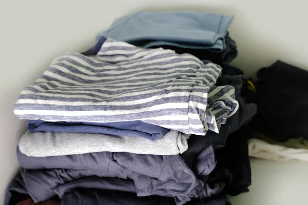 folded clothes in a wardrobe on a shelf, things are stacked, the concept of storing knitted clothes, cleaning the room, putting things in order at home, daily routine