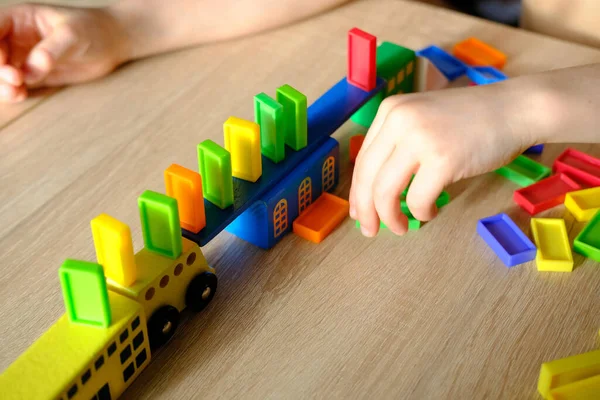 Çocukların ellerinde renkli tahta küpler, dominolar, çocuk 7-9 yaşları ev yapar, araba yuvarlar, inşaat konsepti, yaratıcılığın gelişimi, motor becerileri, sabır.