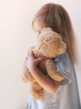 little child, blonde girl 3 years old plays with toy, hugs teddy bear, happy childhood, first impressions, tells plush friend about grudges, complains about domestic violence