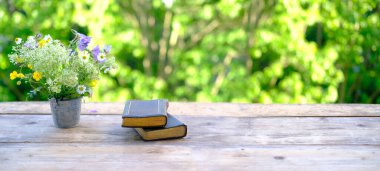 Siyah kapaklı iki eski kağıt kitap bahçedeki ahşap masada, aile incili, arka planda güzel bulanık doğal manzara yeşil yapraklar, kavram eğitimi, bilgi, Hıristiyan dini