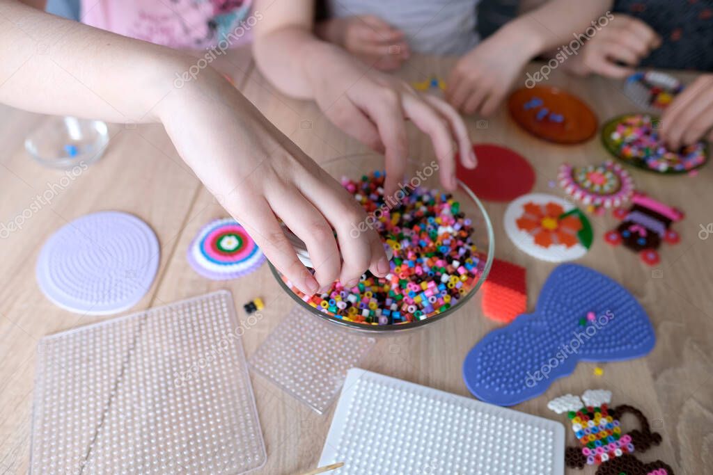 closeup of children's hands creating perler bead patterns, make crafts