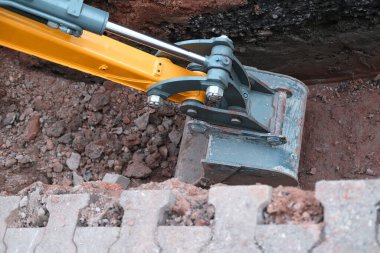 Kazı kovası toprağı sokak siperlerinde kazıyor, kentsel iletişimi onarma konsepti, binalara elektrik şebekeleri kurma, yer altında iletişim için optik fiber döşeme