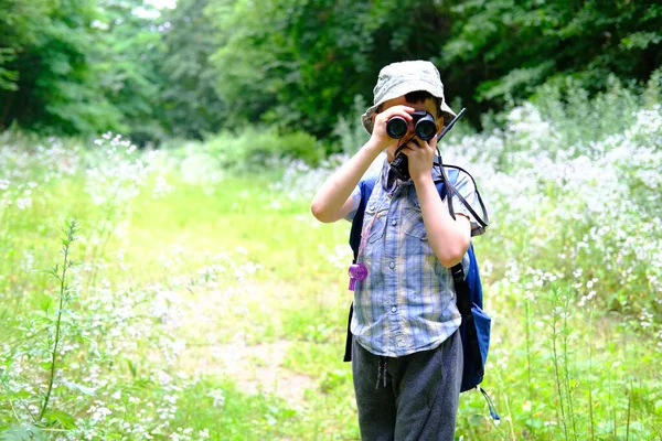 8年の子供 パナマの帽子の少年 手でウォーキートーキーとシャツをプレイした森の中に立って 双眼鏡 オリエンテーリング 野生での生存のハイキングの概念を注意深く見てください — ストック写真