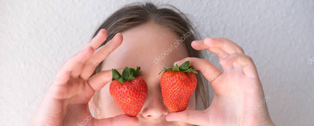 fresh strawberries in hands of child, cheerful girl 14-15 years old, fresh vitamin fruit, binocular eyes, concept of wholesome eating, healthy food for children, good appetite