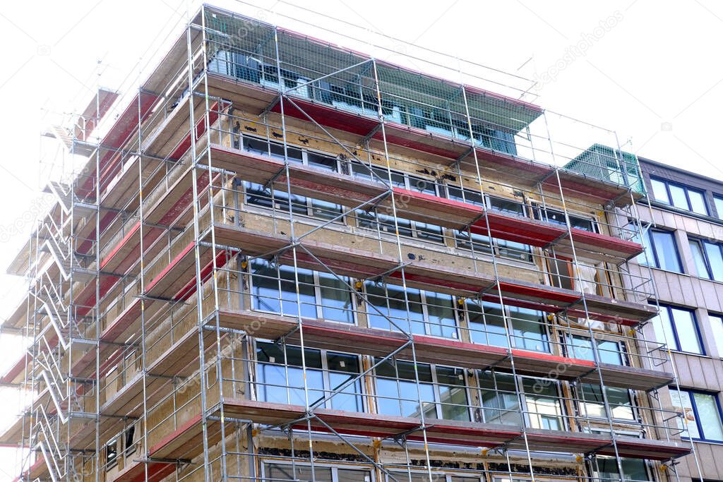 construction site, metal assembly scaffolding near walls of new multi-storey building, construction site with materials for construction of buildings in city