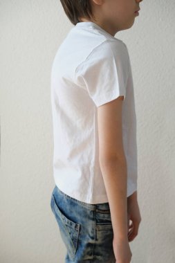 10 yaşında beyaz tişörtlü bir çocuk yan yana duruyor, iyi duruş, dik duruş, çocuklukta omurga eğriliğinin önlenmesi, sağlık kavramı, omurganın güçlendirilmesi.
