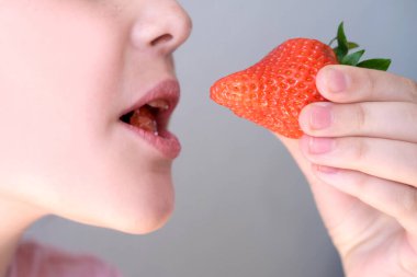 Taze çilekler çocuğun elinde, neşeli kız 14-15 yaşlarında, taze vitamin meyvesi ağızda lezzetli böğürtlen, sağlıklı beslenme konsepti, çocuklar için sağlıklı yiyecekler.