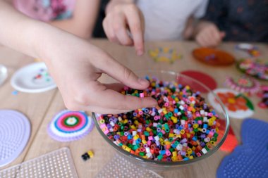 Çocuk ellerine yakın çekim yapmak, perler boncuk desenleri yaratmak, termomomomomozik tekniği, boncuk şekilleri, boncuk sanatı, ince motor becerilerin kavramsal gelişimi, termomomoelektrik fikirler kullanarak el sanatları yapmak.