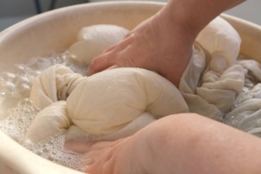 Orta yaşlı bir kadının elleri havuzda yıkanır. Yıkanma öncesi kirli çarşaflar, ev işleri konsepti, rutin ev işleri, temizlik, çamaşır makinesi arızası, seçici odaklanma.