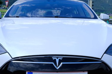 beyaz Tesla hafif elektrikli araba ofis önündeki park yerinde duruyor, alternatif enerji geliştirme konsepti, elektrikli araç üretimi, elektrik enerji deposu, Innsbruck, Avusturya - Haziran 2022