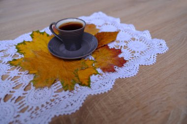 Gri kahve fincanının yakın plan resmi olarak dantelli beyaz peçeteye uzanan çay ve kahve içme zamanı, kafeinin sağlık üzerindeki etkisi, sonbahar havası konsepti.