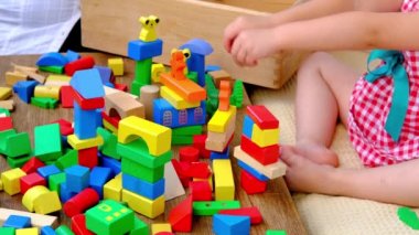 little four year old boy has fun playing at home with wooden blocks building tower under isolation, development of fine motor skills, simulation is the leading activity of children