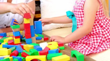 little four year old boy has fun playing at home with wooden blocks building tower under isolation, development of fine motor skills, simulation is the leading activity of children