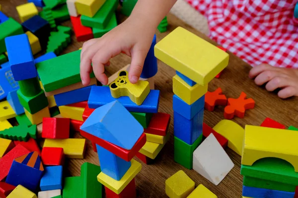 Dört yaşındaki küçük bir çocuk, izolasyon altında ahşap bloklar inşa kulesiyle oynarken eğleniyor, motor becerilerinin geliştirilmesi, simülasyon çocukların en önemli aktivitesidir.