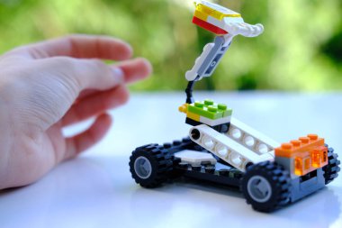 Manipülatörlü transformatör araba, lego parçalarından, ağaçların güzel yeşil arka planından, konsept geliştirme iyi motor becerileri, yaratıcılık, çocuk eğlencesi, Frankfurt - Haziran 2022