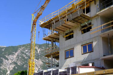 construction site, metal assembly scaffolding near walls of new multi-storey building, building materials, housewarming, mortgage for new housing, modern civil engineering, construction crane