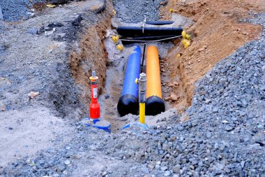 uncovered pipeline construction site, pipes with sand around it for making pipeline for heating system, concept of repairing urban communications, reconstruction of the district heating system