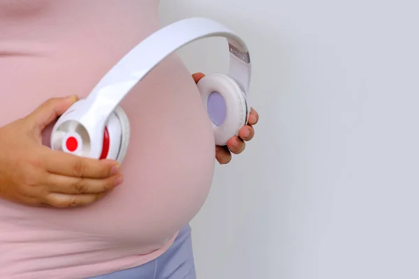 Middle Aged Pregnant Woman Pink Shirt Holds Headphones Her Belly — Zdjęcie stockowe