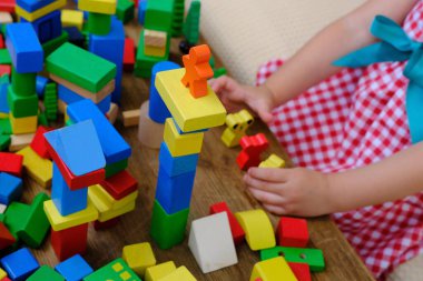little four year old boy has fun playing at home with wooden blocks building tower under isolation, development of fine motor skills, simulation is the leading activity of children