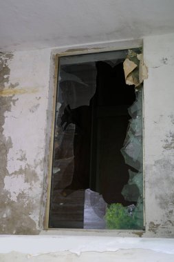 Ortasında delik olan kirli pencere çerçevesi, keskin cam parçaları, konsept çekimi, askeri operasyonlar, bombalama ve roket saldırıları sonucu binaların tahrip edilmesi, patlama dalgası.