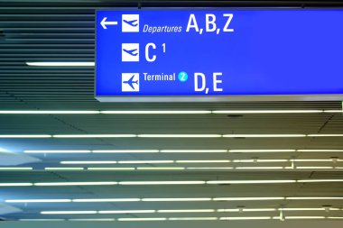 Havaalanı salonunun yakın çekimleri, mavi plakalı kapılar, terminal numarası, Almanya 'daki Frankfurt Havaalanı' ndaki tabelalar, uçağa binmek için doğru kapıyı gösteriyor.