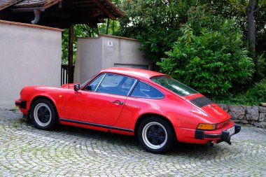 Avrupa 'nın tarihi bölgesindeki evin yakınına park edilmiş kırmızı Porsche arabası, Alman spor araba üreticisi, Hall in Tirol, Avusturya - Haziran 2022