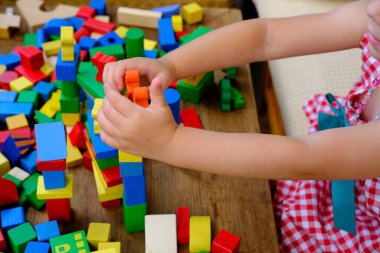 Dört yaşındaki küçük bir çocuk, izolasyon altında ahşap bloklar inşa kulesiyle oynarken eğleniyor, motor becerilerinin geliştirilmesi, simülasyon çocukların en önemli aktivitesidir.