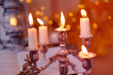 stack of vinyl discs, notes, burning candles in a candlestick, magical objects in a dim room, an atmosphere of magic, the development of imagination, Halloween holiday, cozy musical holiday mood