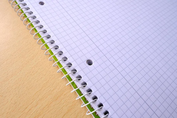 Top view of opened checkered notebook on a spiral for a notice in school or office lie on a light table, close-up. Free space for text. Business or education concept