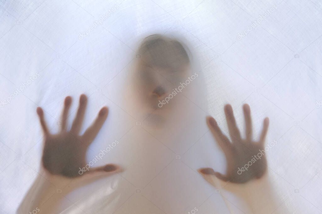 eerie blurry hands and face of girl, victim of violence behind window, dense fabric, wrap, ghost, spirit trying to reach out from afterlife, concept of friday 13th, nightmares, halloween horror