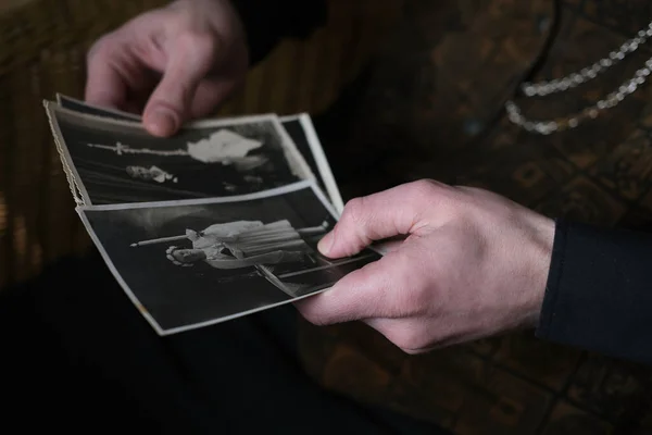 close-up male hand holding old vintage photos in sepia color 50s, 60s, carefully sorts out family values, concept of family tree, genealogy, memory of ancestors, family ties, childhood memories