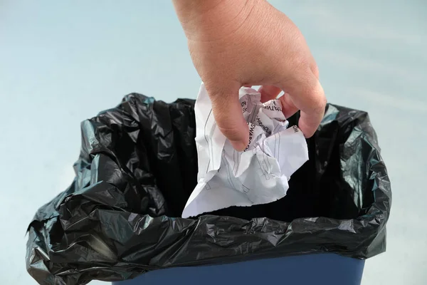 woman puts wrinkled paper in a recycling bin, close-up hands, concept of household waste disposal, different types of garbage into different bins, waste recycling, reuse, destruction of documents