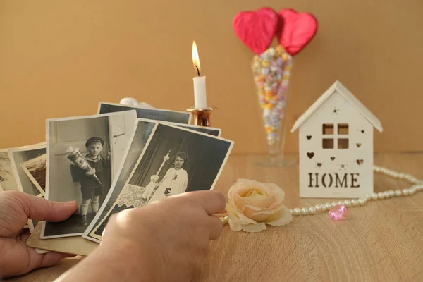 close-up female hand holding old vintage photos, romantic still life in love style, candles burning, cupid with wings, concept of family tree, genealogy, childhood memories