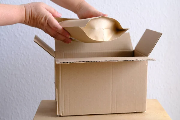 close-up of female hands take out package from open cardboard box of medium size postal box with wrapping paper, a parcel, delivery of ordered goods, online shopping, timely delivery to customers