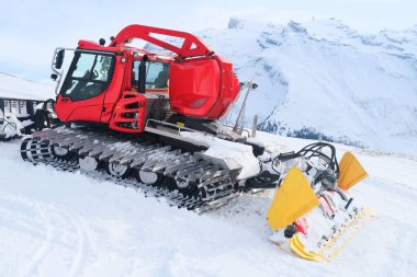 İsviçre Alpleri 'ndeki dağ başlarındaki kırmızı traktör yoğun kardan, kış etkinliğinden, arabayla seyahat etmekten, kışın kamu hizmetleri sorunlarından arınır.