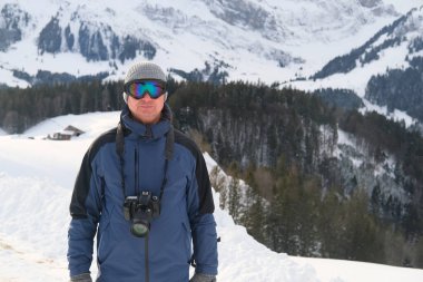 Kameralı yaşlı bir adam, dağ yürüyüşçüsü kış manzarasına hayran, spor konsepti, sağlıklı yaşam tarzı, kış etkinliği, güzel kış doğal manzarası, kışın beyaz ormanda yürüyor.