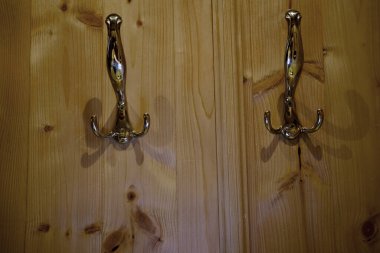 Koridordaki duvarda ahşap paneller, parlak metal palto askıları, prova odası, konsept, otelde konfor, daire, askılara elbise asma.