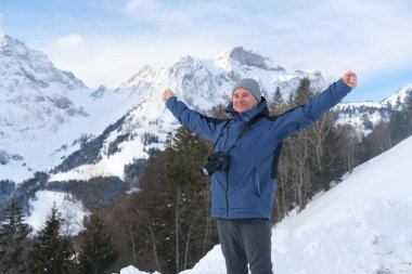 Kameralı yaşlı bir adam, dağ yürüyüşçüsü kış manzarasına hayran, spor konsepti, sağlıklı yaşam tarzı, kış etkinliği, güzel kış doğal manzarası, kışın beyaz ormanda yürüyor.