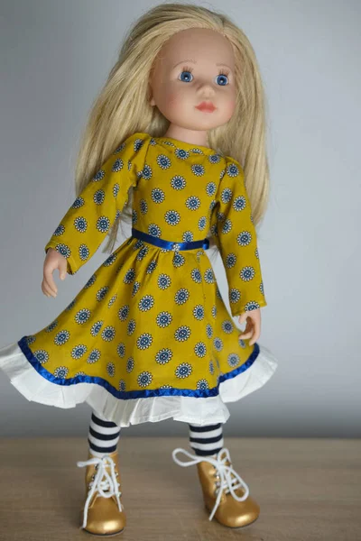 doll with long blond hair in smart clothes, in ayellow dress and boots, concept children\'s toy, doll fashion, hobby, for girls, happy childhood