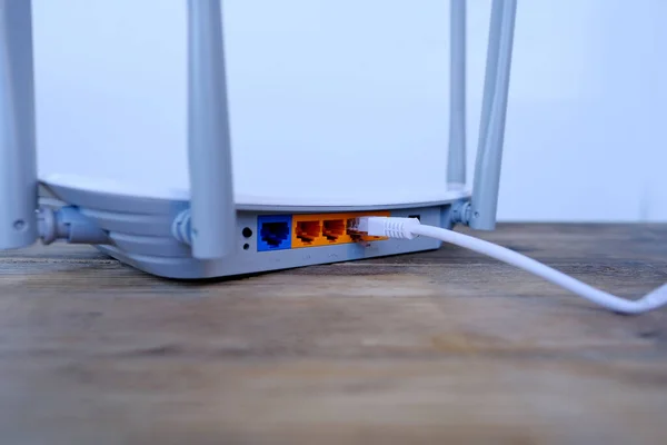 white cable is plugged into the port of Wi-Fi router, modern wireless Router with four non-removable external antennas for better search and signal transmission, concept high speed data processing