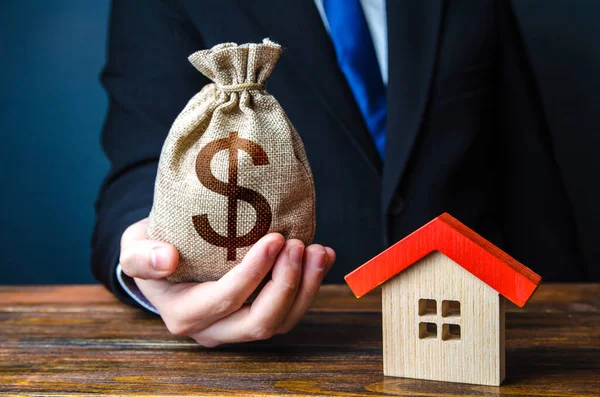 男は家の近くにお金袋を持っている 住宅ローンを発行する銀行の承認 有利な条件 低金利 住宅購入 不動産への投資 財産評価 — ストック写真