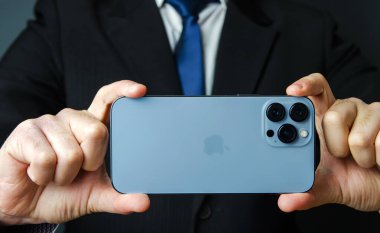 Kherson, Ukrayna, 2 Aralık 2021: IPhone bir iş adamının elinde maksimum 13 profesyonel mavi renk. İş dünyasında iletişim, online iş ve internet üzerinden alışveriş. Sosyal ağlar ve uzak çalışma.
