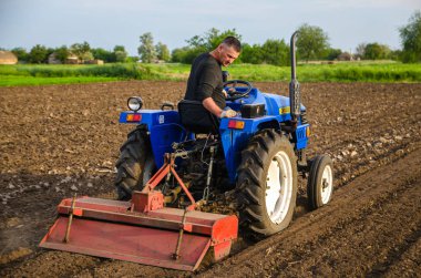 Kherson oblast, Ukraine - May 29, 2021: Senior farmer works in the field on a tractor. Seasonal worker. Loosening , cultivation. Plowing. Recruiting and hiring employees for work. Milling soil.