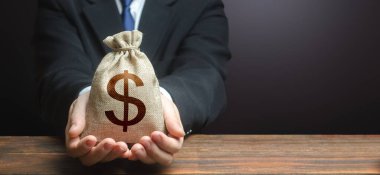 İşadamı bir dolar para çantası tutuyor. Bağış alıyorum. İpotek, kredi onayı. Kolay Para. Maaş, sosyal yardım, kâr. Yatırımları cezbediyor. Tasarruf hesabına. Nakit para. Bankacılık ve kredi.