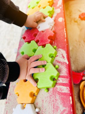 Çocuk kum havuzunda renkli bulmacalarla oynuyor. Seçici odak