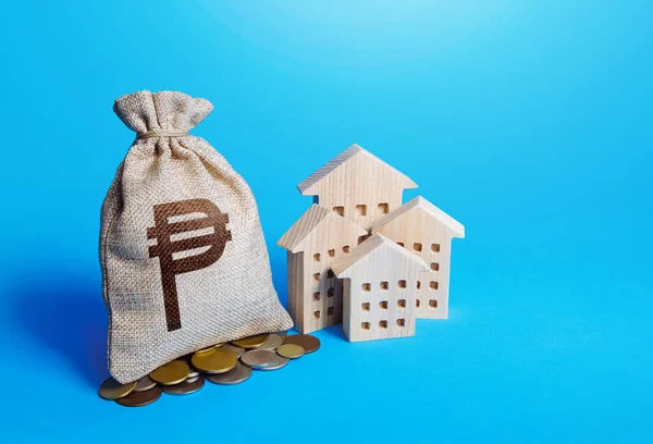 Houses and philippine peso money bag. Real estate investment and rental business. Property value. Home taxation. Residential or commercial property income. Fair market price. Municipal budget.