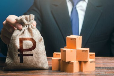 Businessman holds russian ruble money bag and boxes with goods. Import and export. Purchase and sale of goods, trade and commerce. Business income. Payment of taxes and fees. Advertising budget