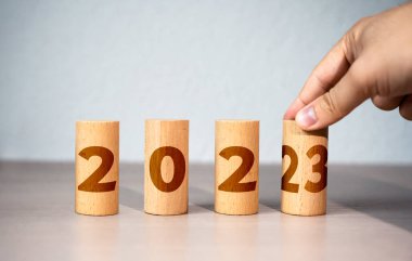 The hand changes the year from 2022 to 2023. New Year and Christmas holidays. Trends and changes, new challenges . Plans and goals. Trends and ideas. Summing up. Future. Business planning. Analytics.